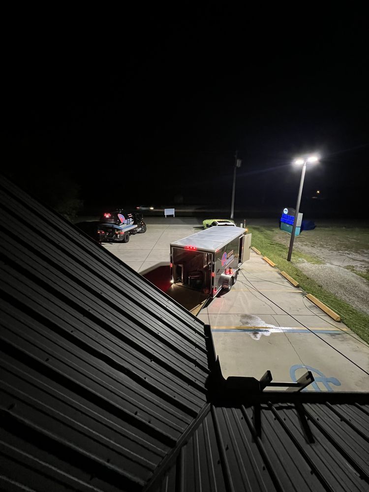 A view of a parking lot at night from the roof of a building.