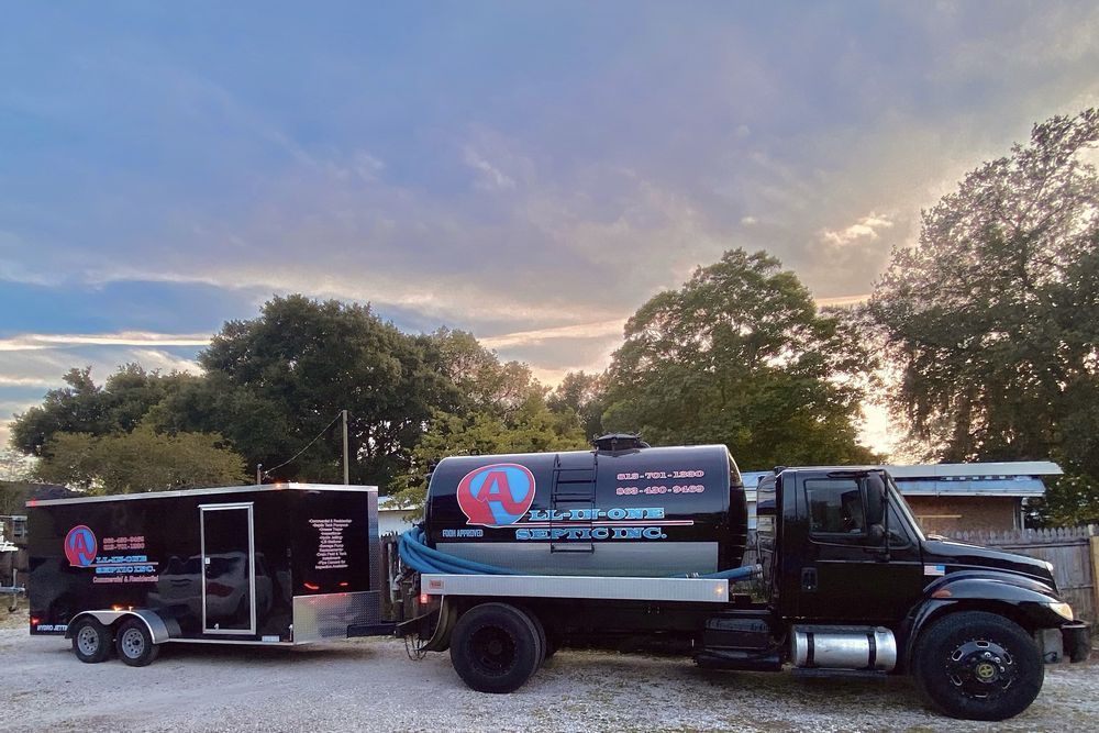 A black truck with a trailer attached to it is parked in a parking lot.