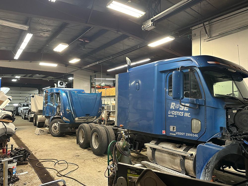 A blue semi truck is being repaired in a garage.
