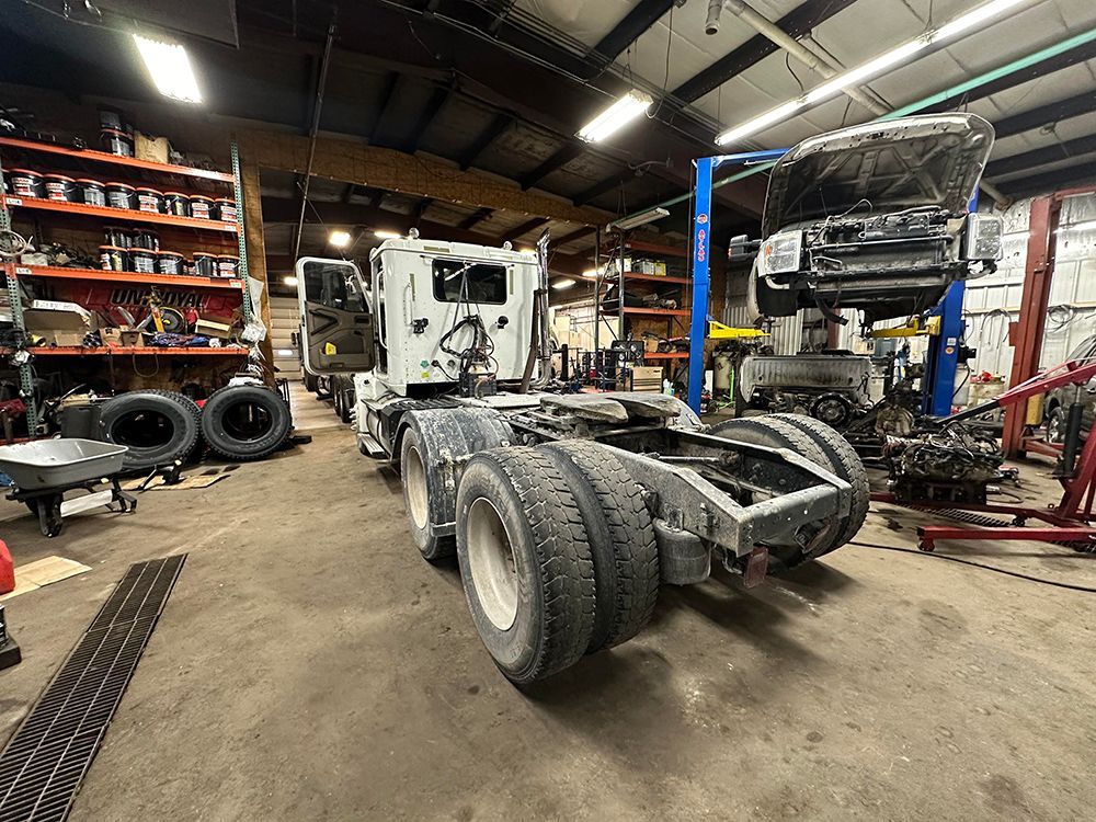 A truck is sitting in a garage with the hood up.