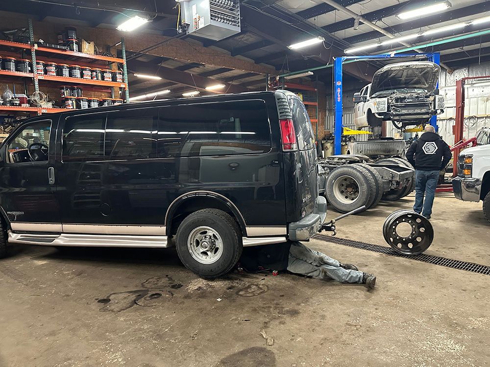 A man is laying under a van in a garage.
