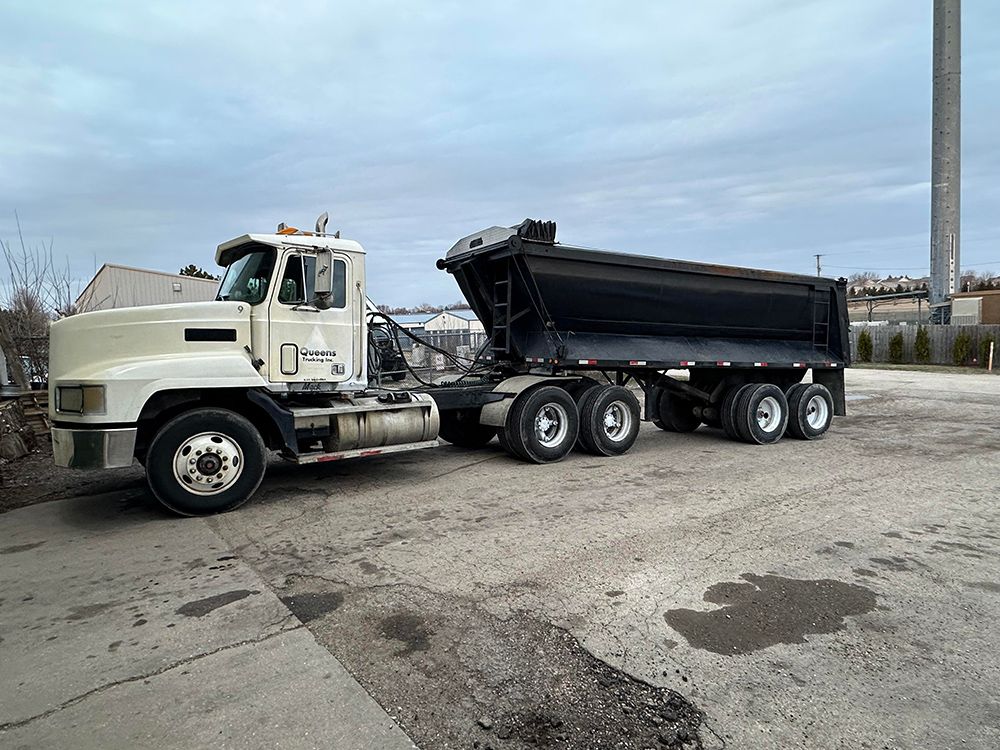 A dump truck with a trailer attached to it is parked in a parking lot