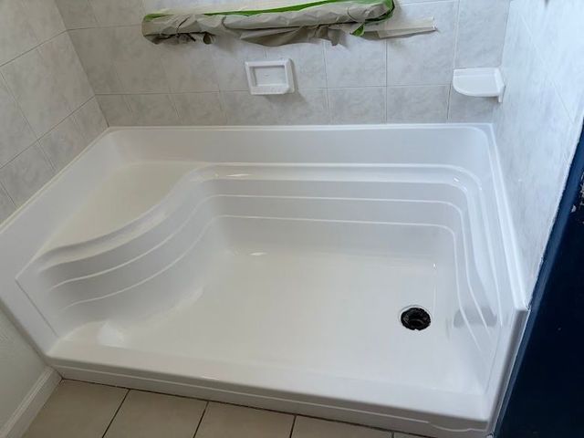 White walk-in shower with built-in bench, grab bar, and tiled walls.