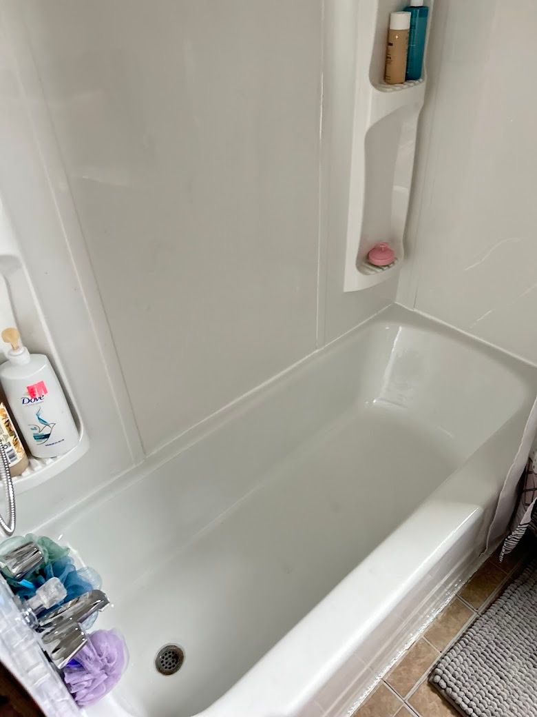 White bathtub with built-in shelves holding toiletries and a shower curtain partially visible.