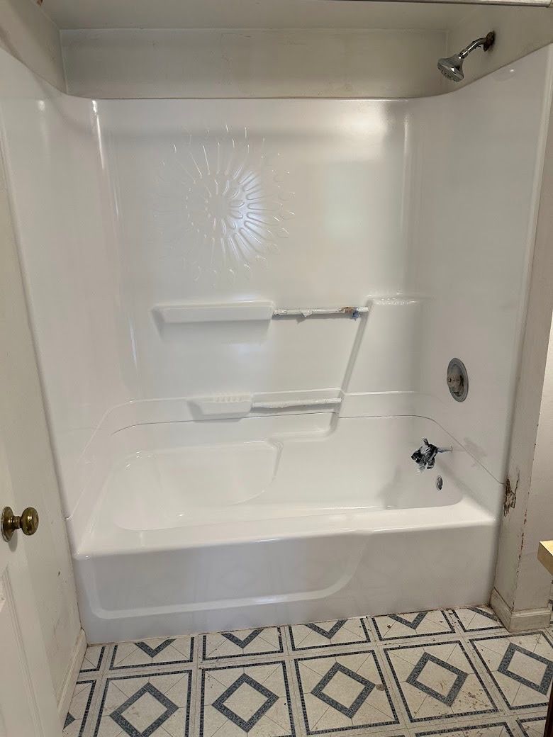 White bathroom tub with built-in seat, grab bars, and patterned tile floor