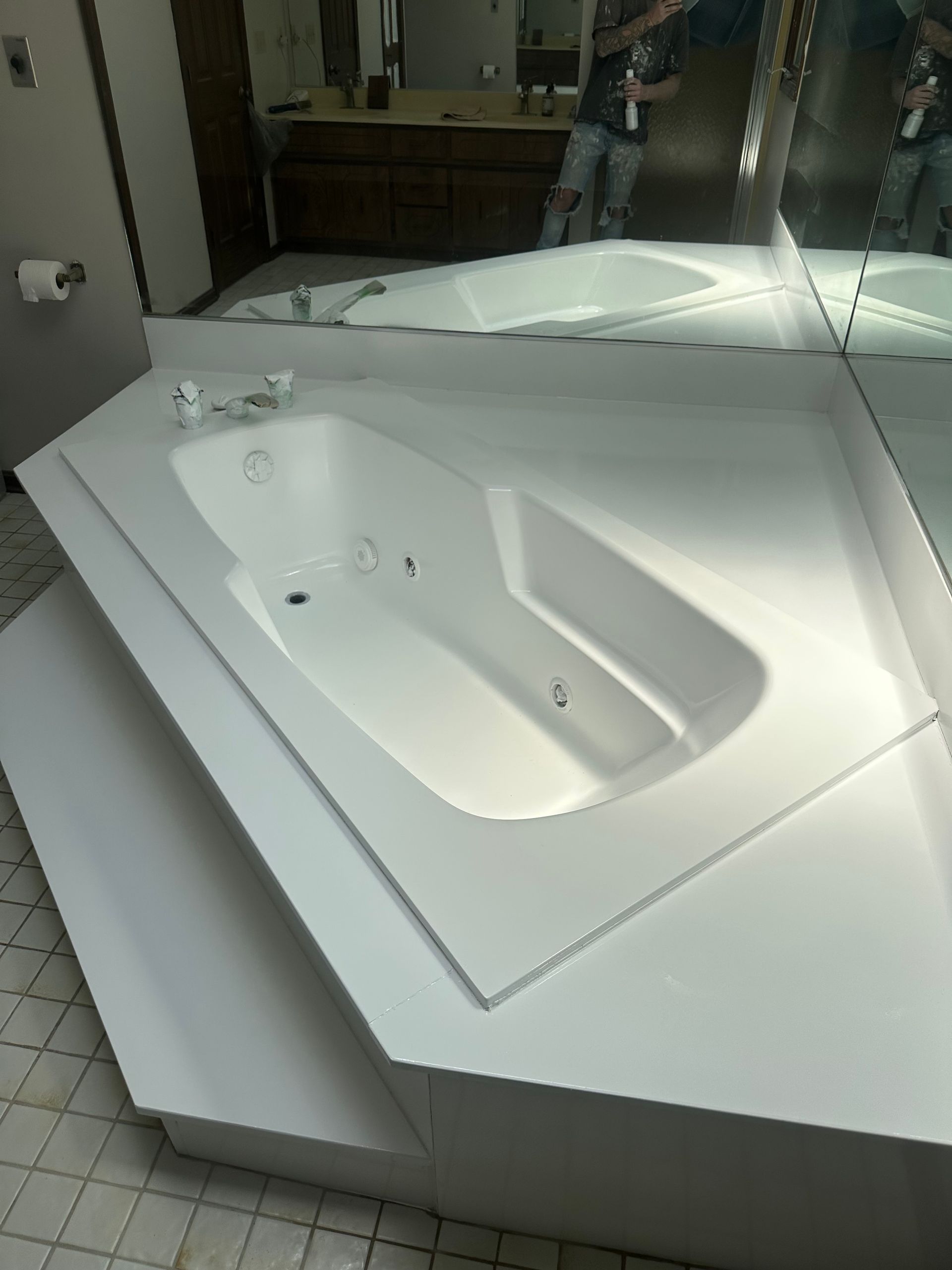 White bathroom sink with mirrored reflection and tiled floor in a restroom.