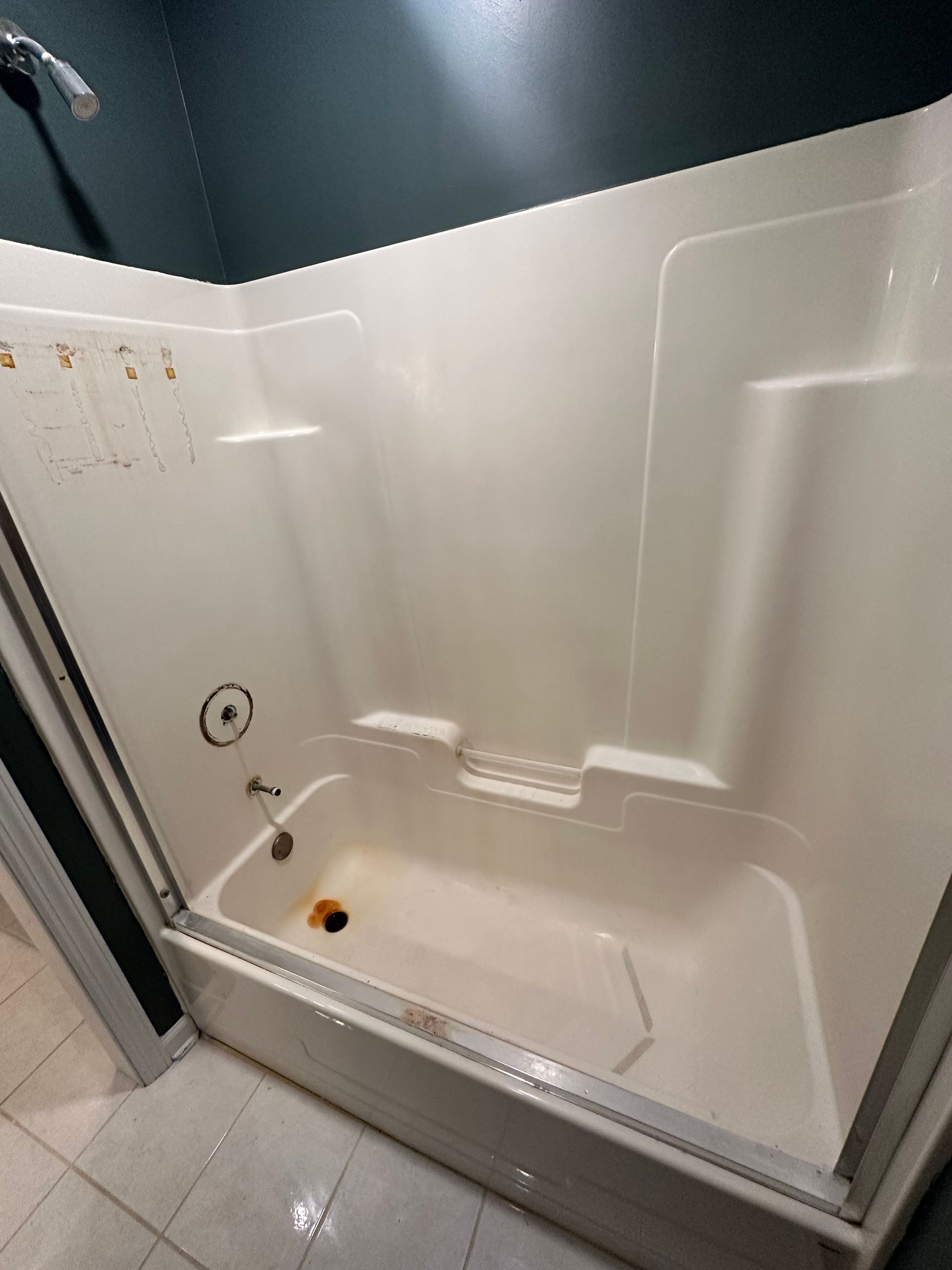 White shower/tub stall with grab bars and built-in seat in a bathroom at a slight angle