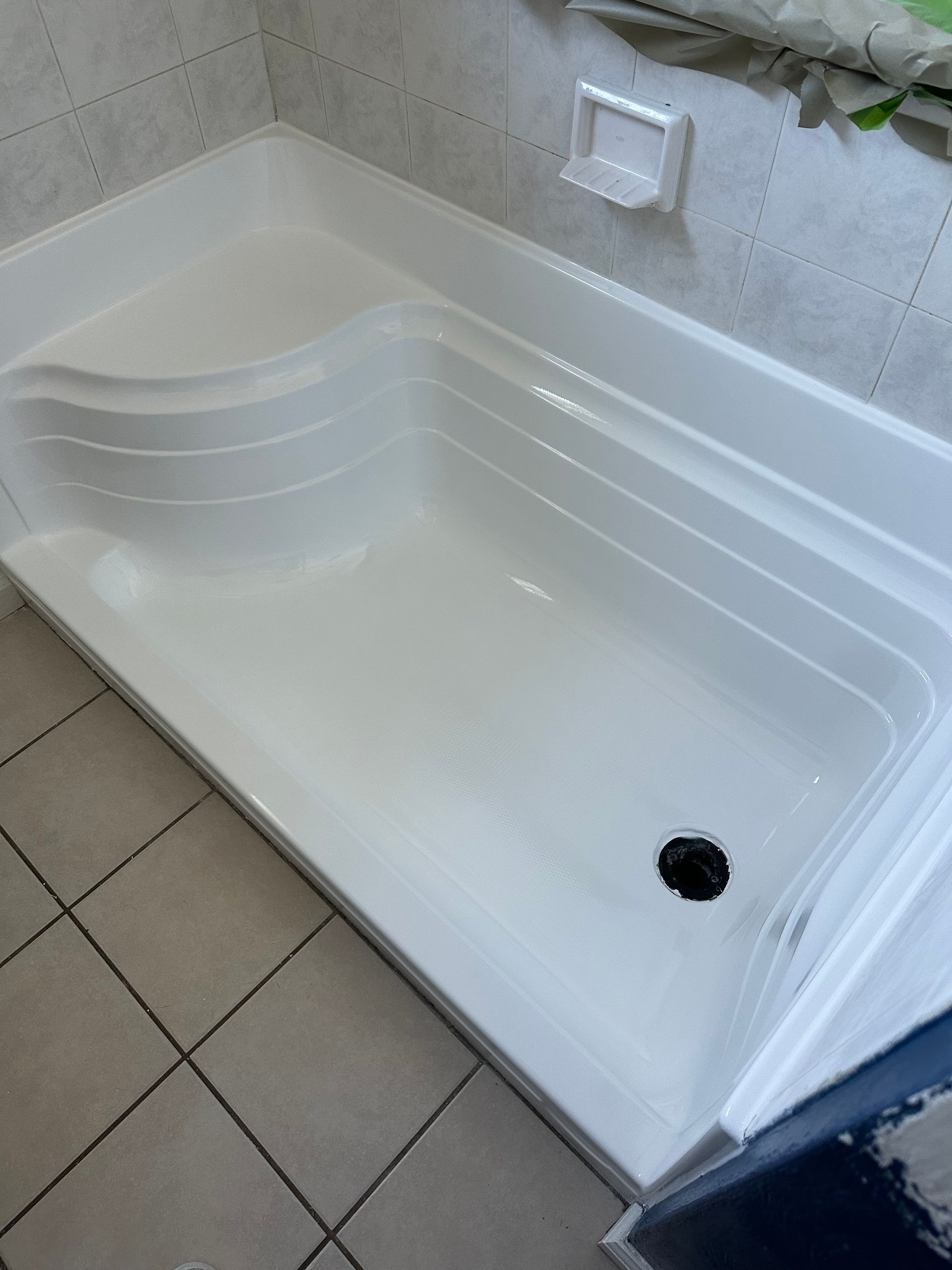 White walk-in shower with built-in seat, tiled walls, and a drain.