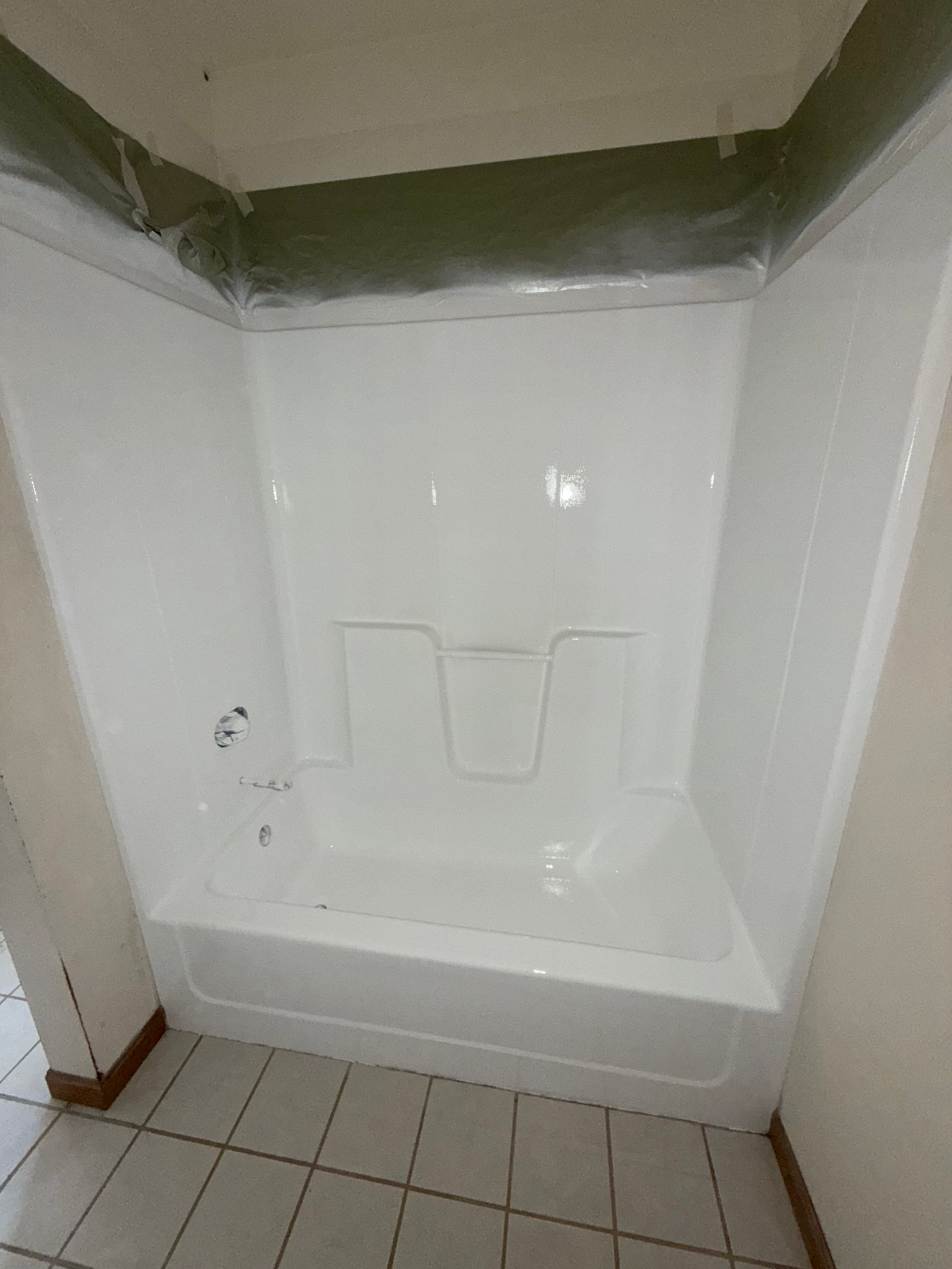 White shower stall with built-in seat and tiled floor in a bathroom corner