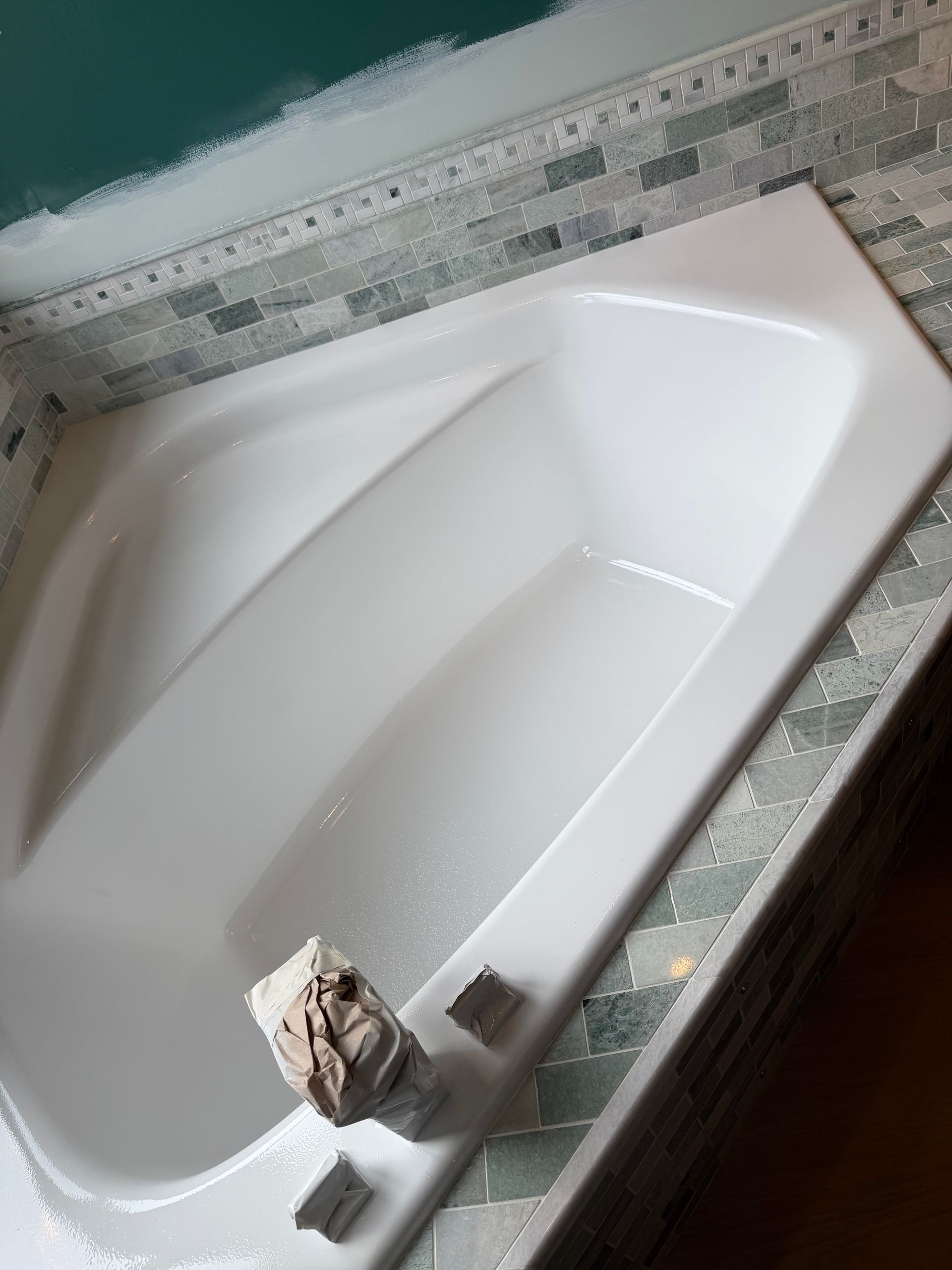 White bathtub with a cloth and soap dish on the rim in a tiled bathroom