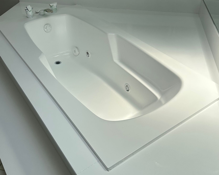 White built-in bathtub with angled sides in a modern bathroom interior