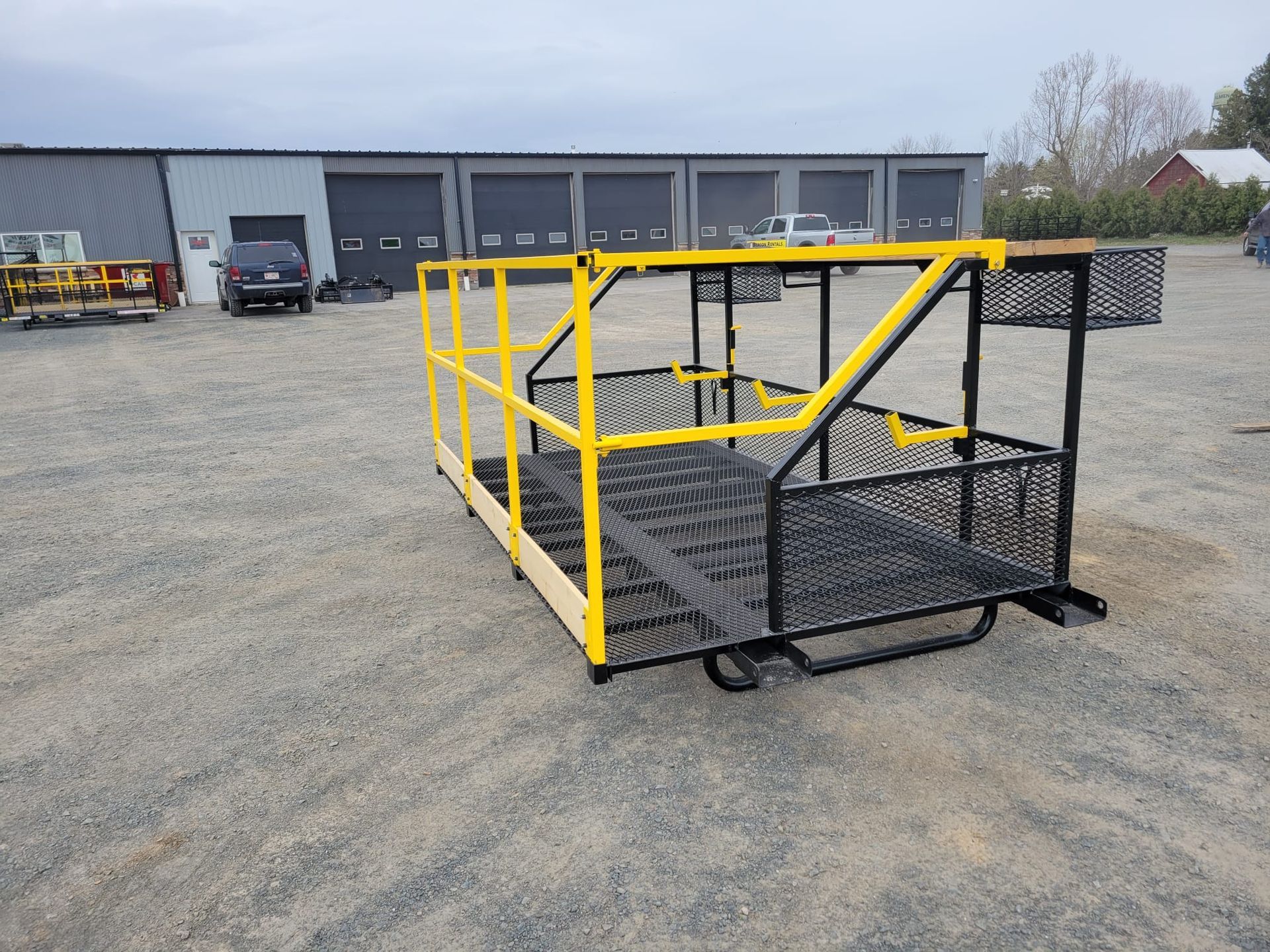 Yellow and black metal work platform on gravel in front of a building.