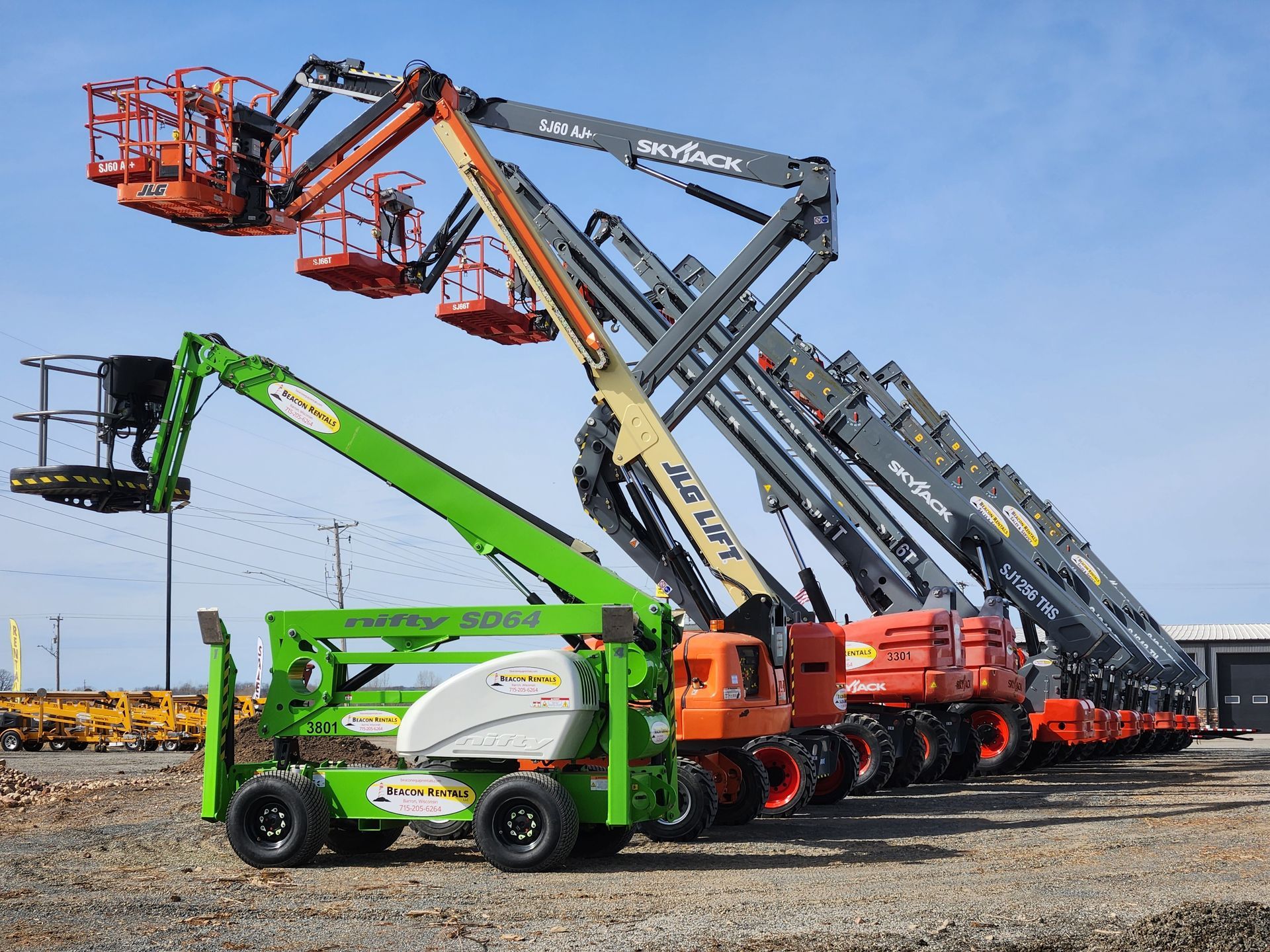 Line of construction lifts, various colors, parked outdoors.