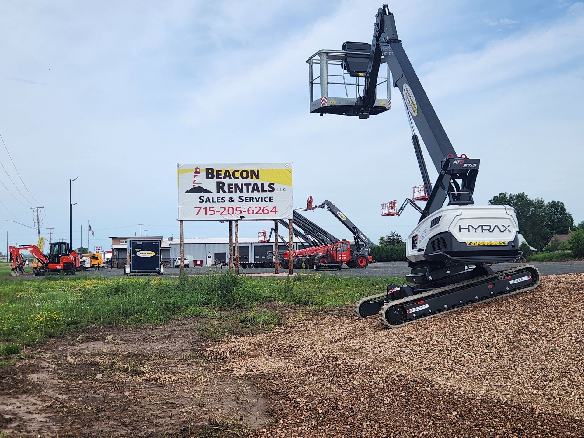 A white and black lift is on a wood chip pile in front of Beacon Rentals building.