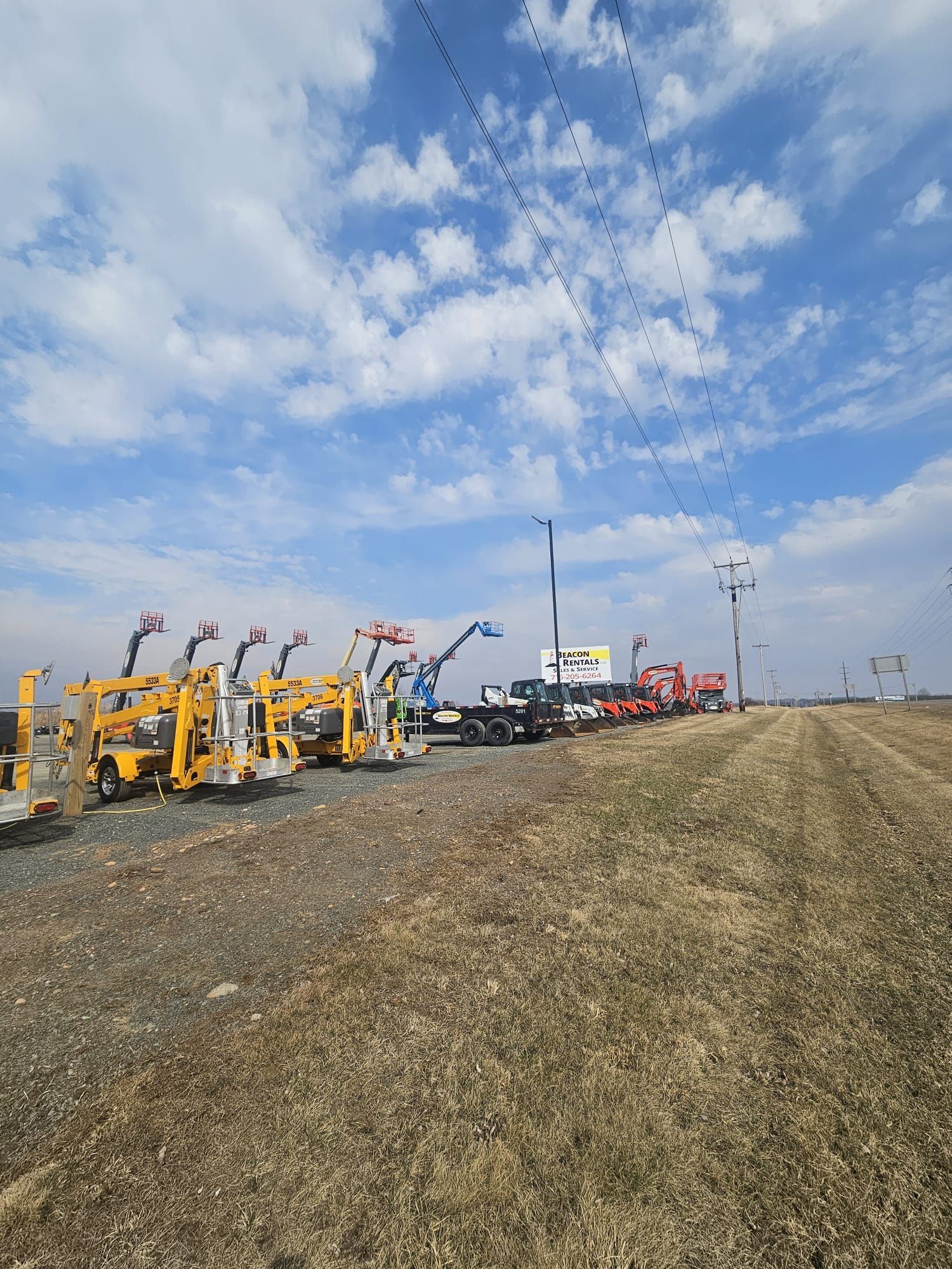 Construction vehicles parked on a dirt lot under a cloudy sky.