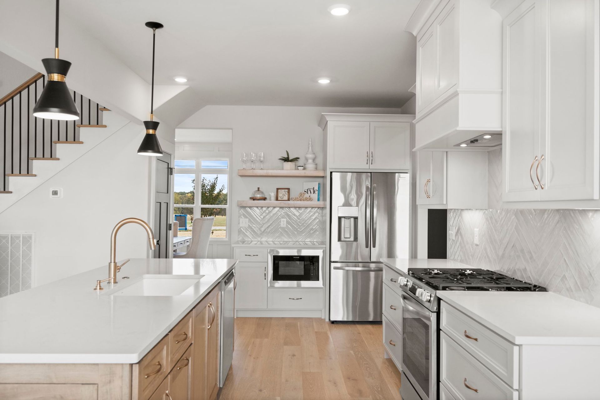 A kitchen in a new home with white cabinets and stainless steel appliances.