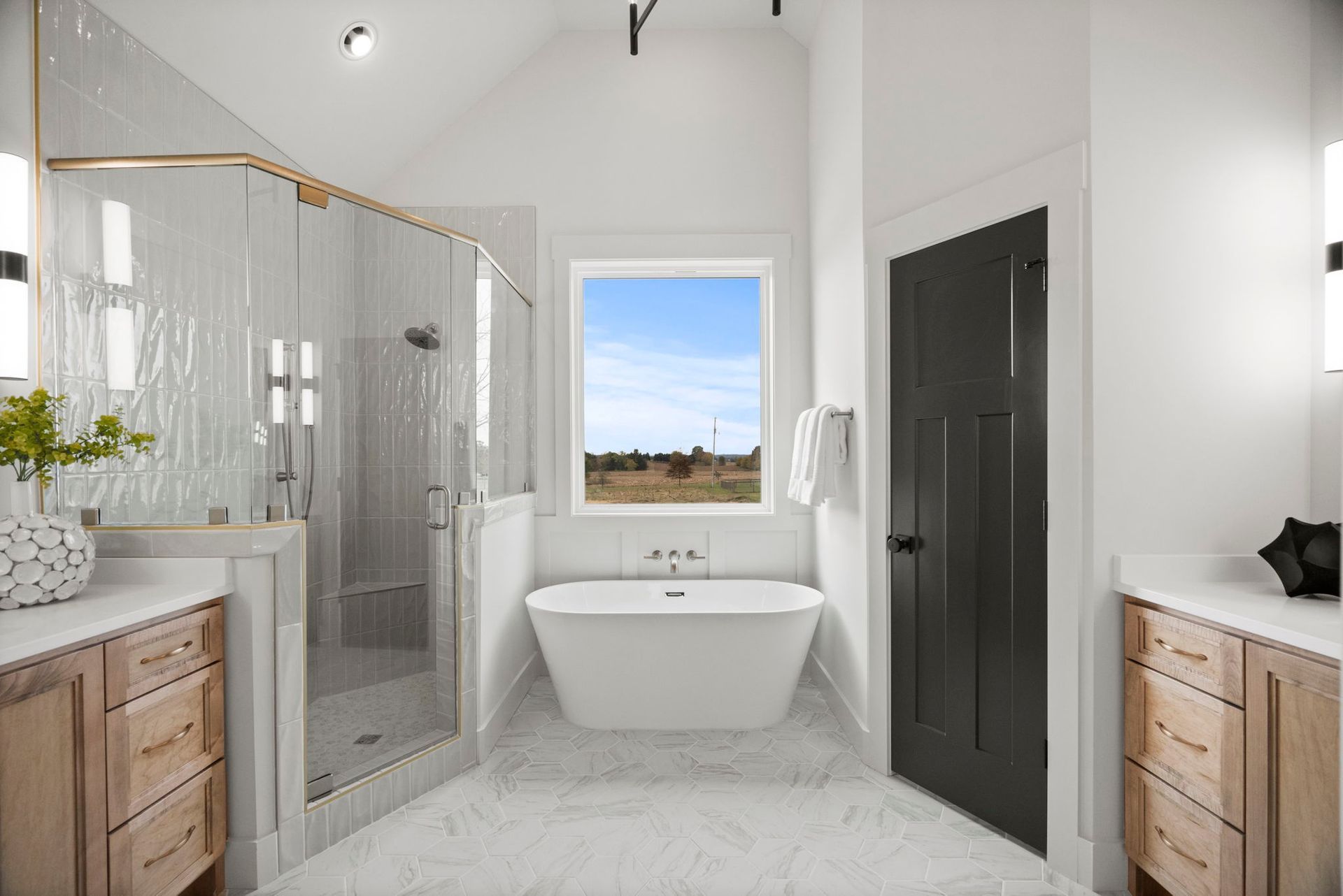 A bathroom with two sinks , a tub , a shower and a window.