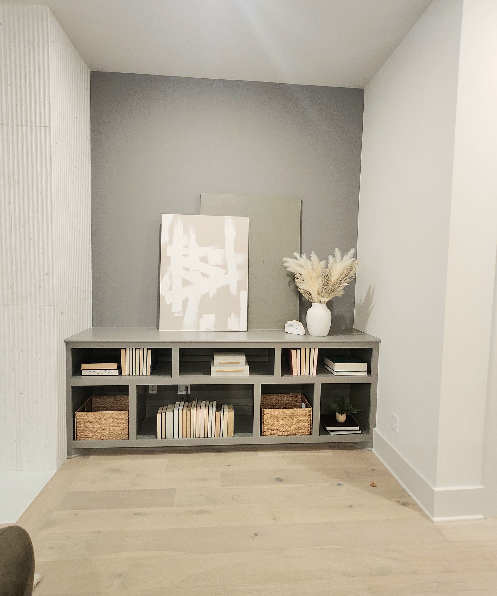 A living room with a shelf filled with books and a picture on the wall.