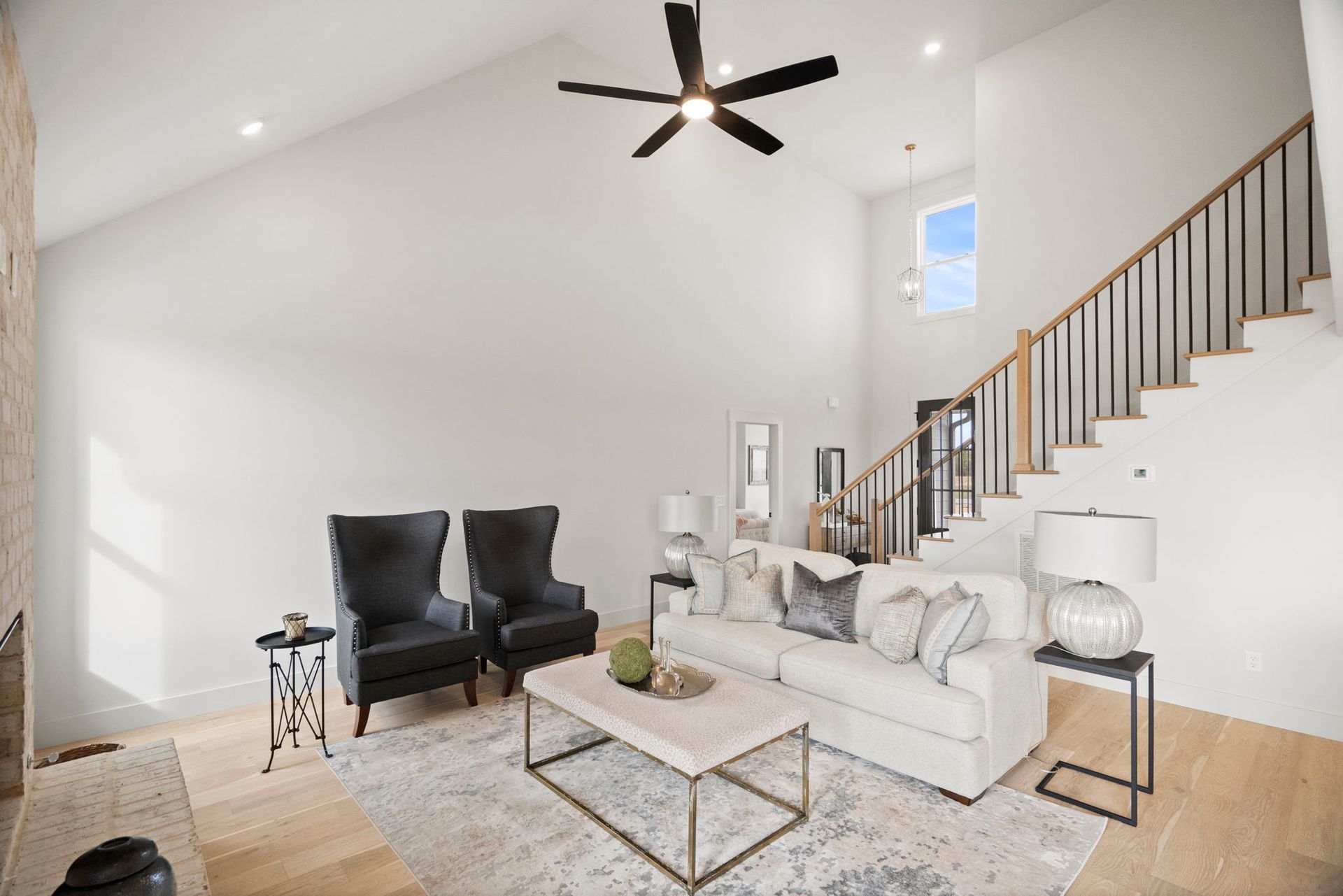 A living room with a couch , chairs , coffee table and stairs.