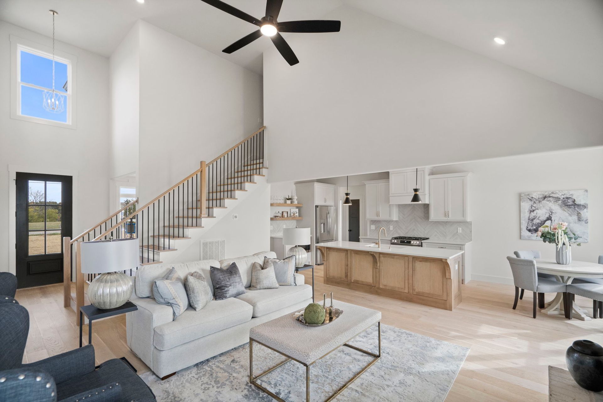 A living room with a couch , coffee table , chairs and a ceiling fan.