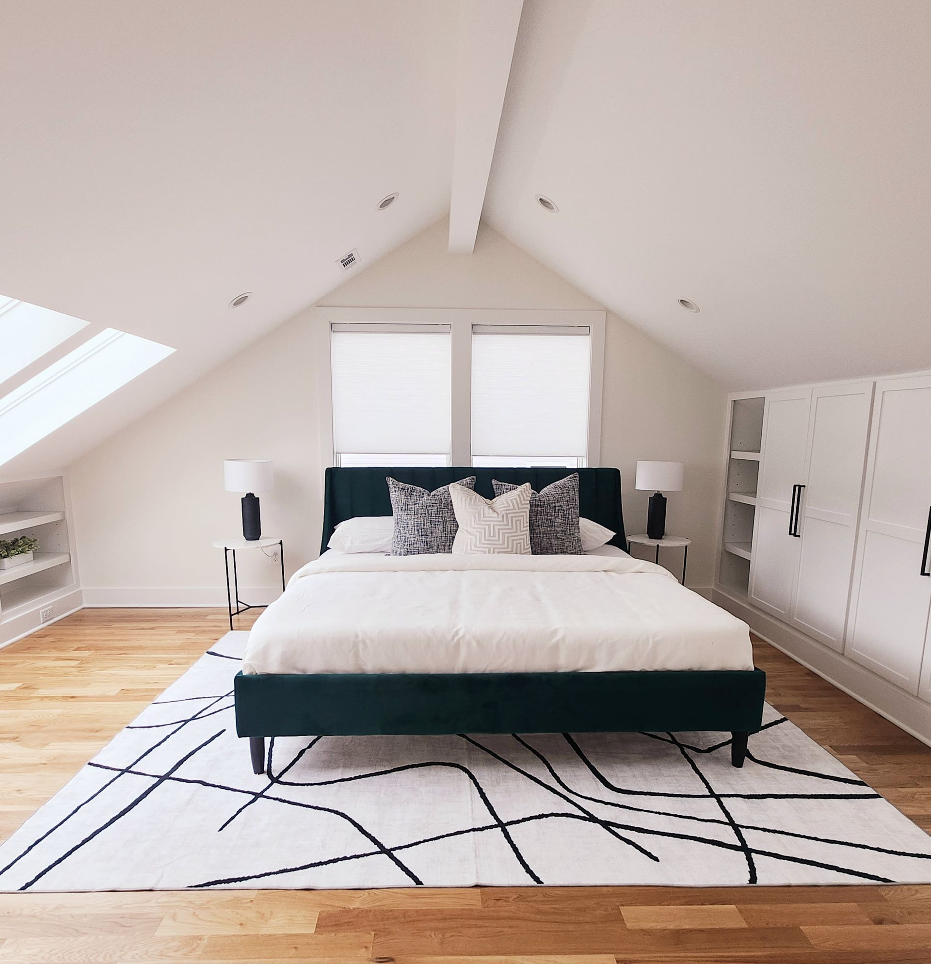A bedroom with a king size bed and a rug on the floor.