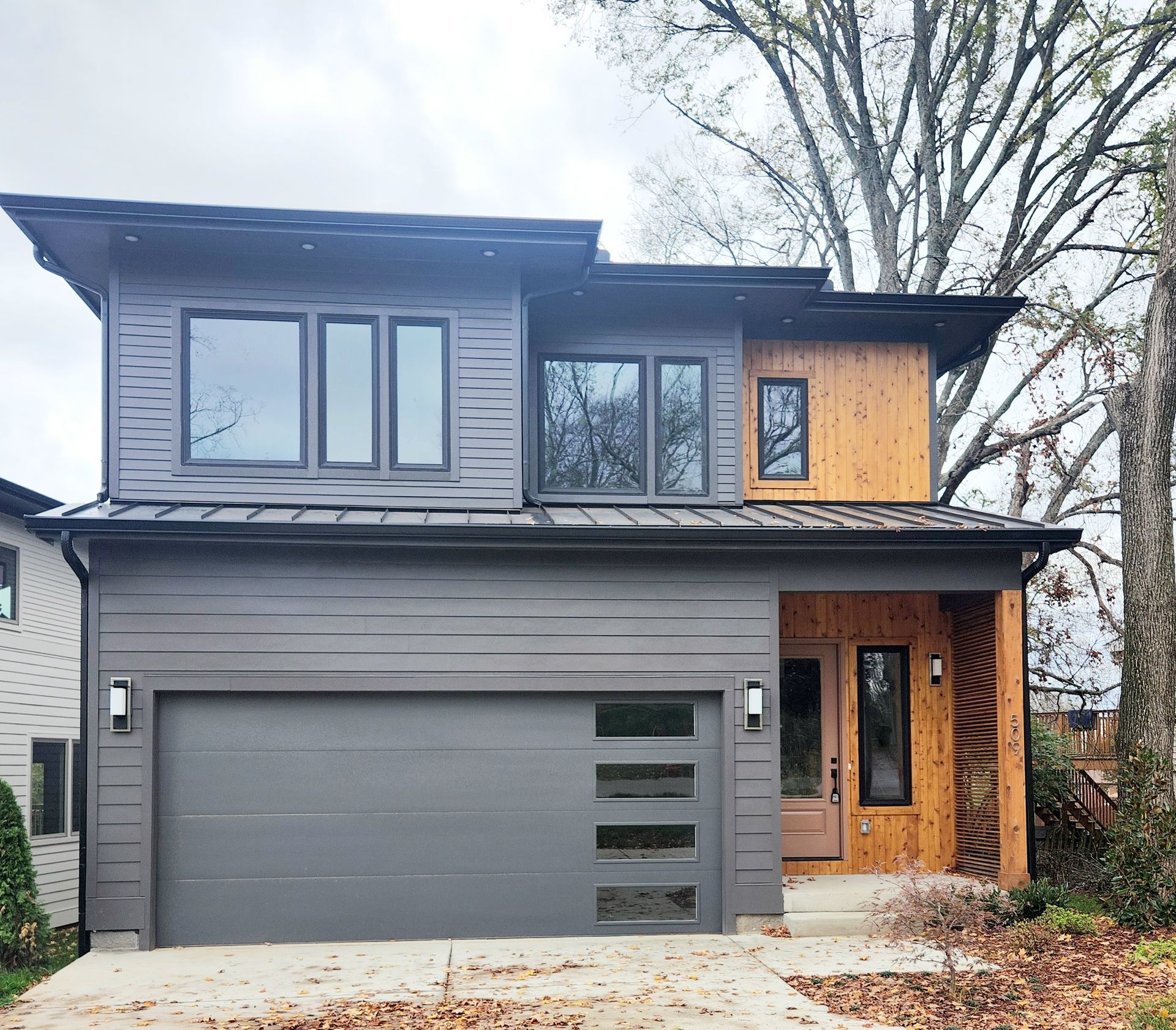 A modern house with a gray garage door and a wooden door.