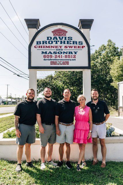 A group of people standing in front of a sign for davis brothers chimney sweep.