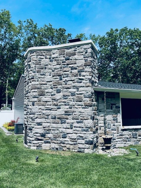 A house with a large stone chimney on the side of it.