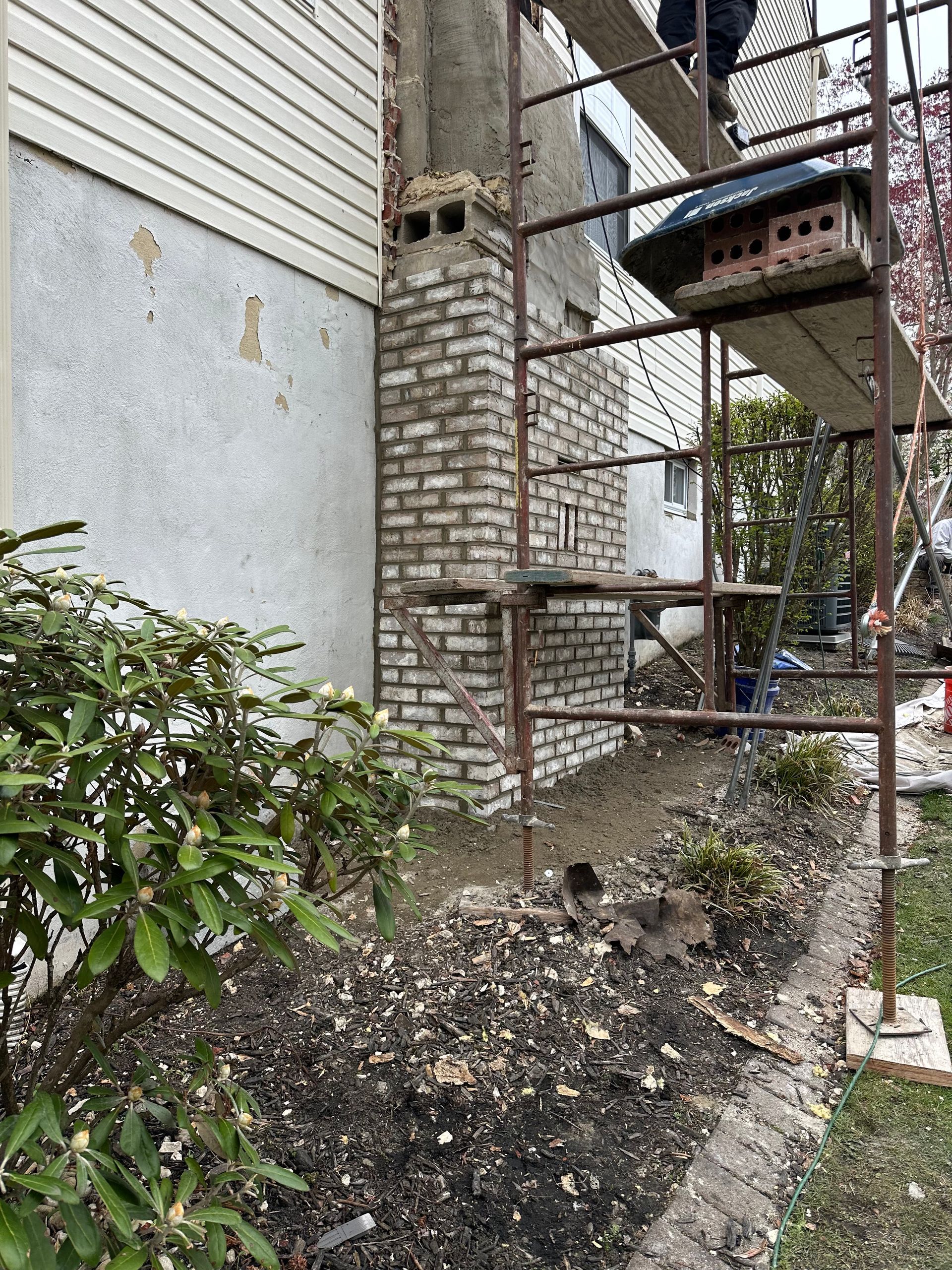 A brick chimney is being removed from the side of a house.