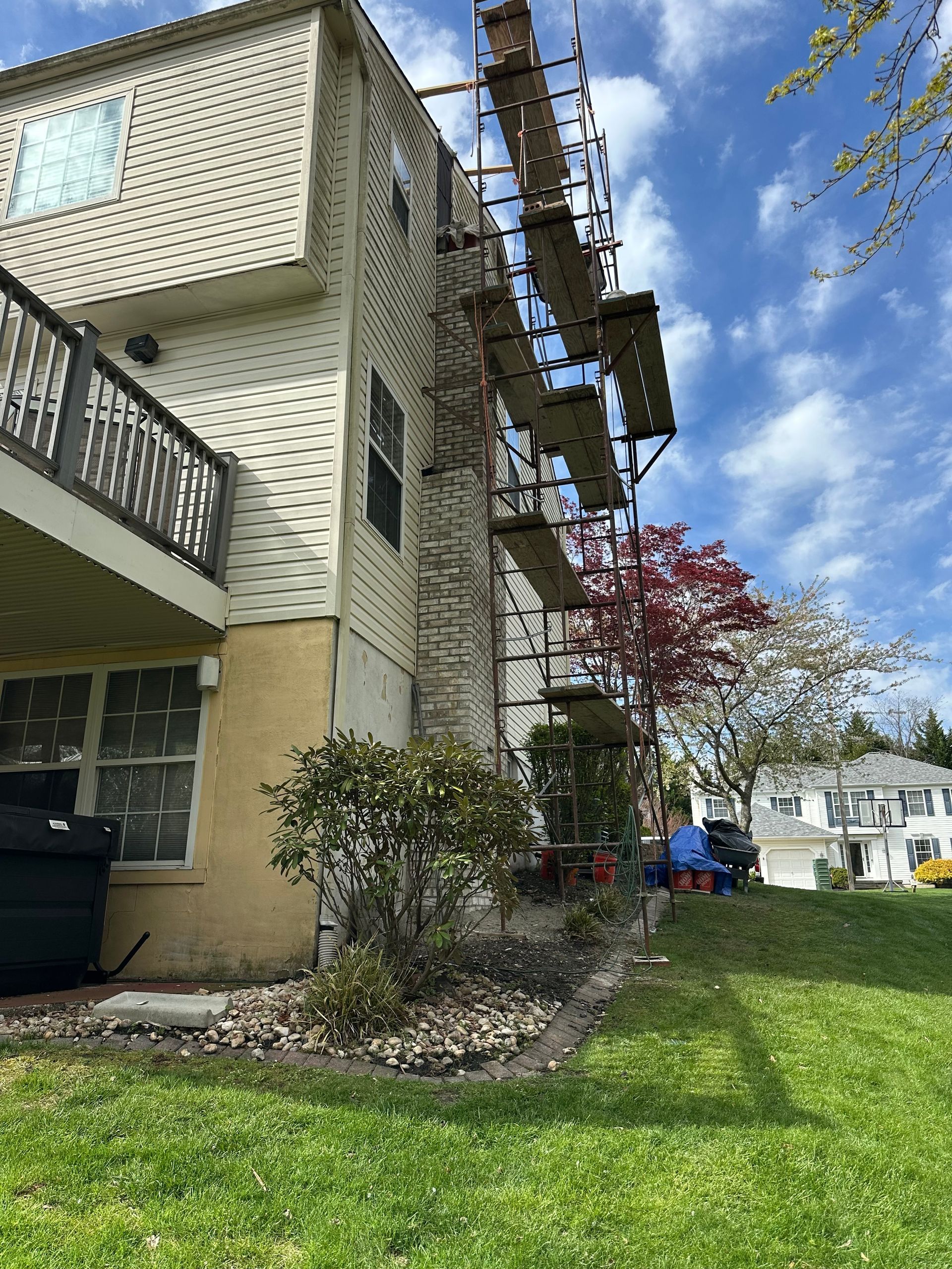 A house with scaffolding on the side of it is being painted.