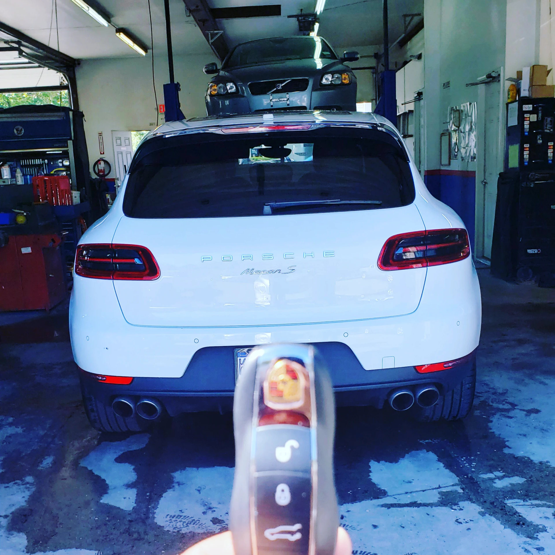 A person is holding a remote control in front of a porsche car