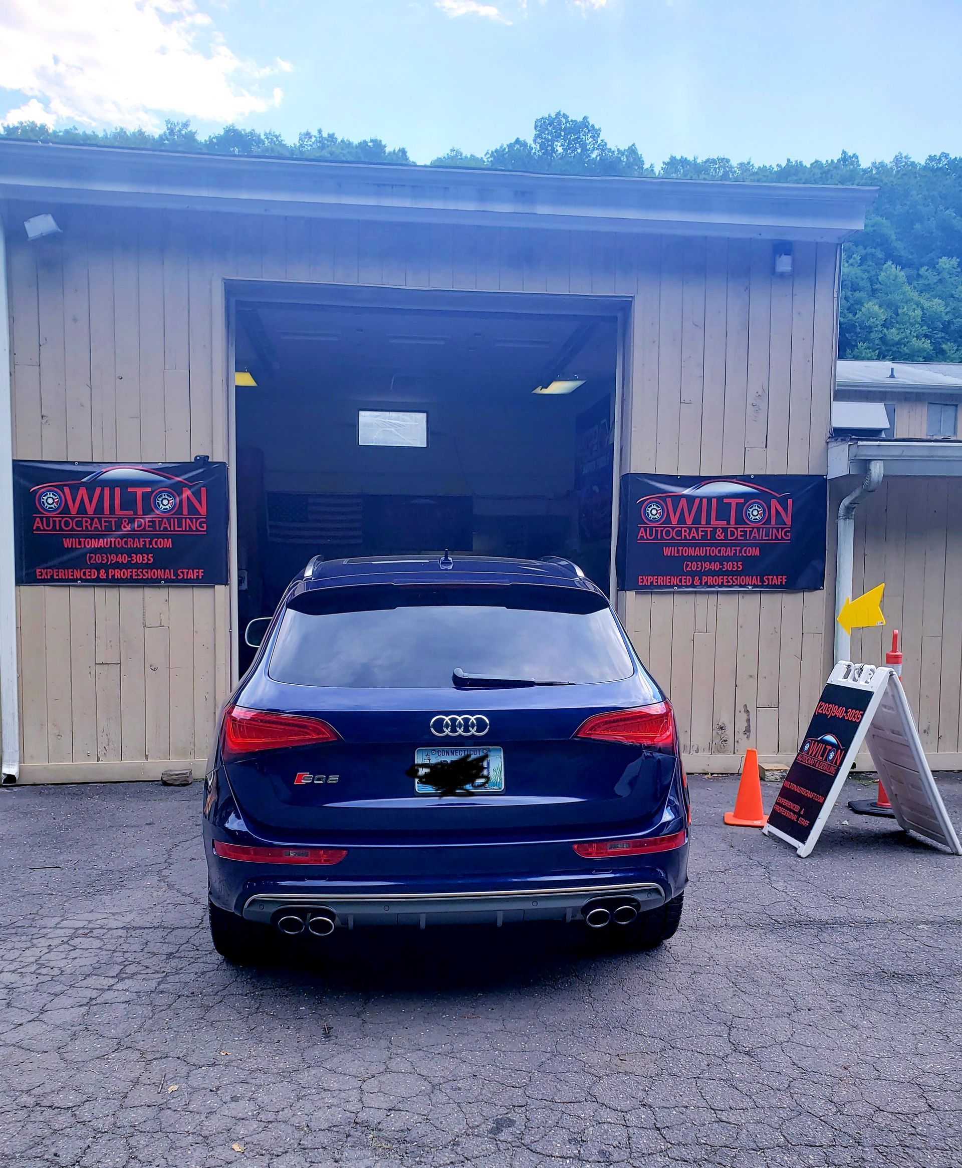 A blue car is parked in front of a garage.