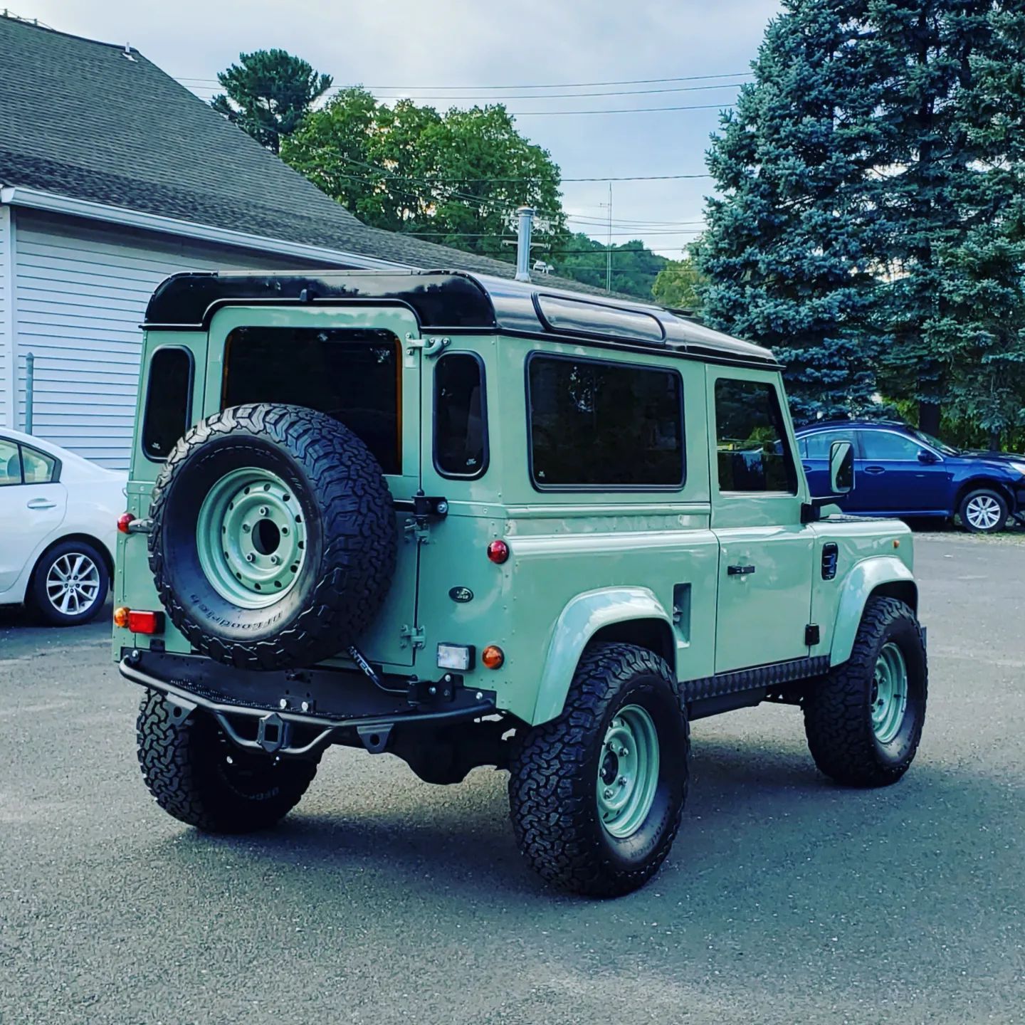 A green land rover defender is parked in a parking lot