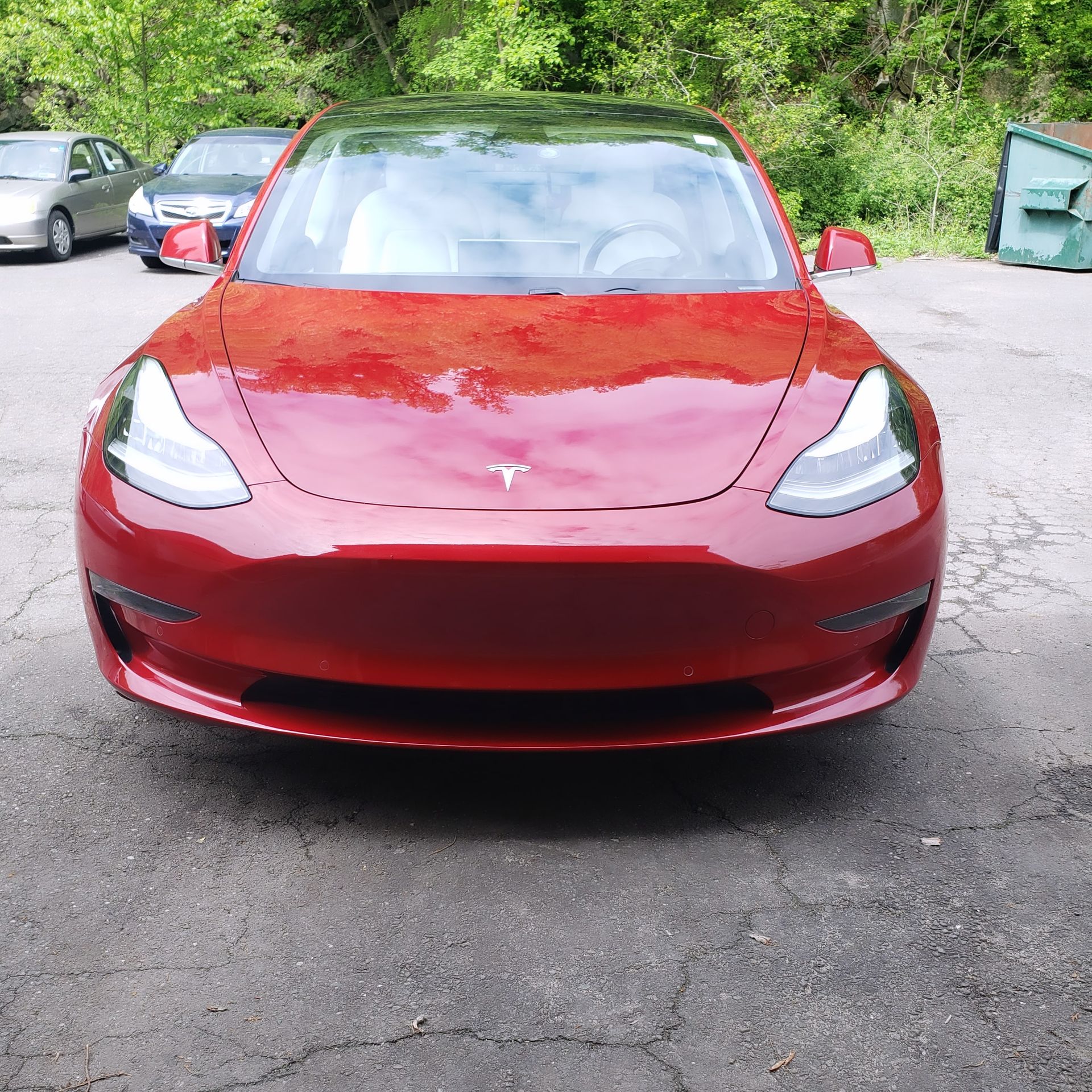A red tesla model 3 is parked in a parking lot