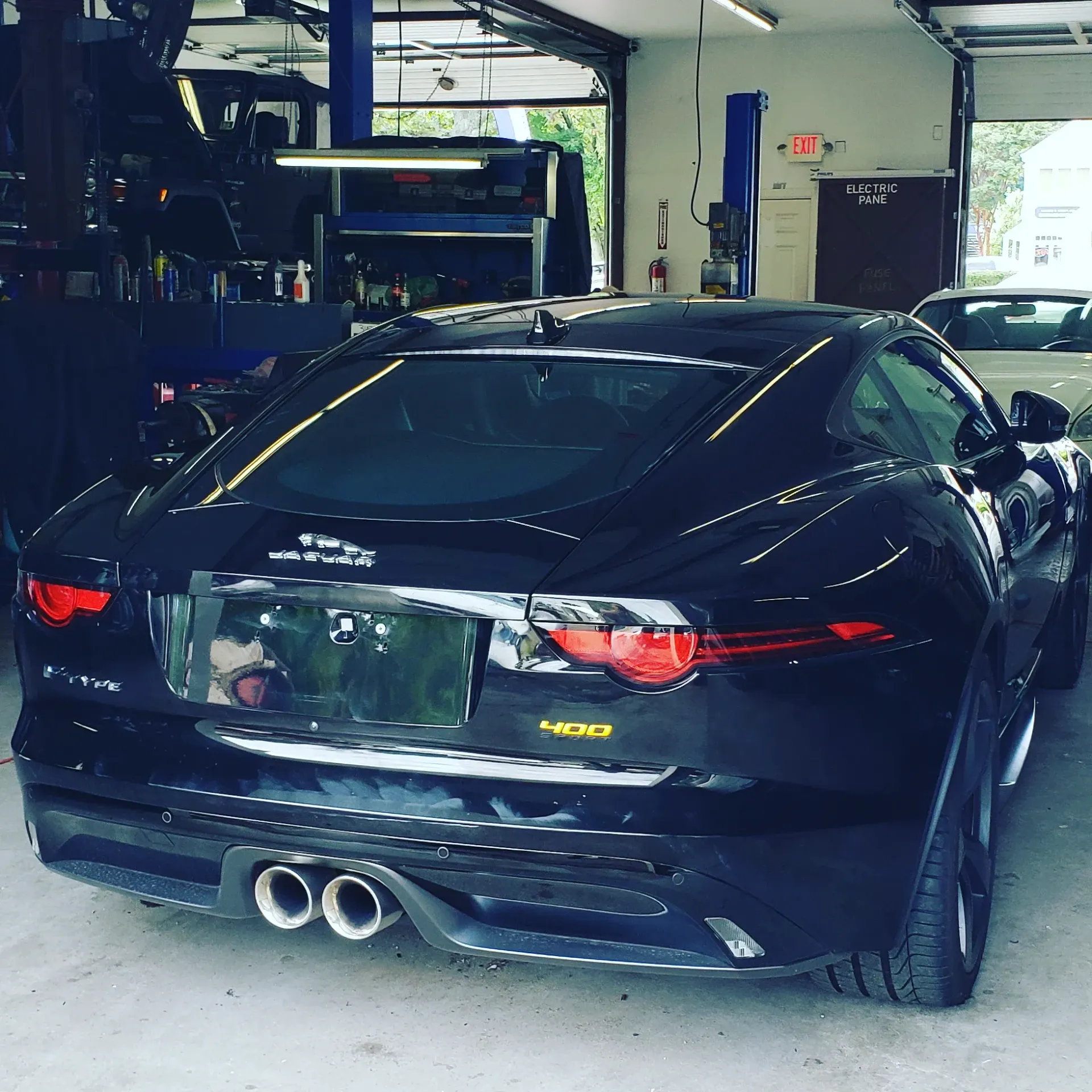 A black car is parked in a garage with a license plate that says jaguar