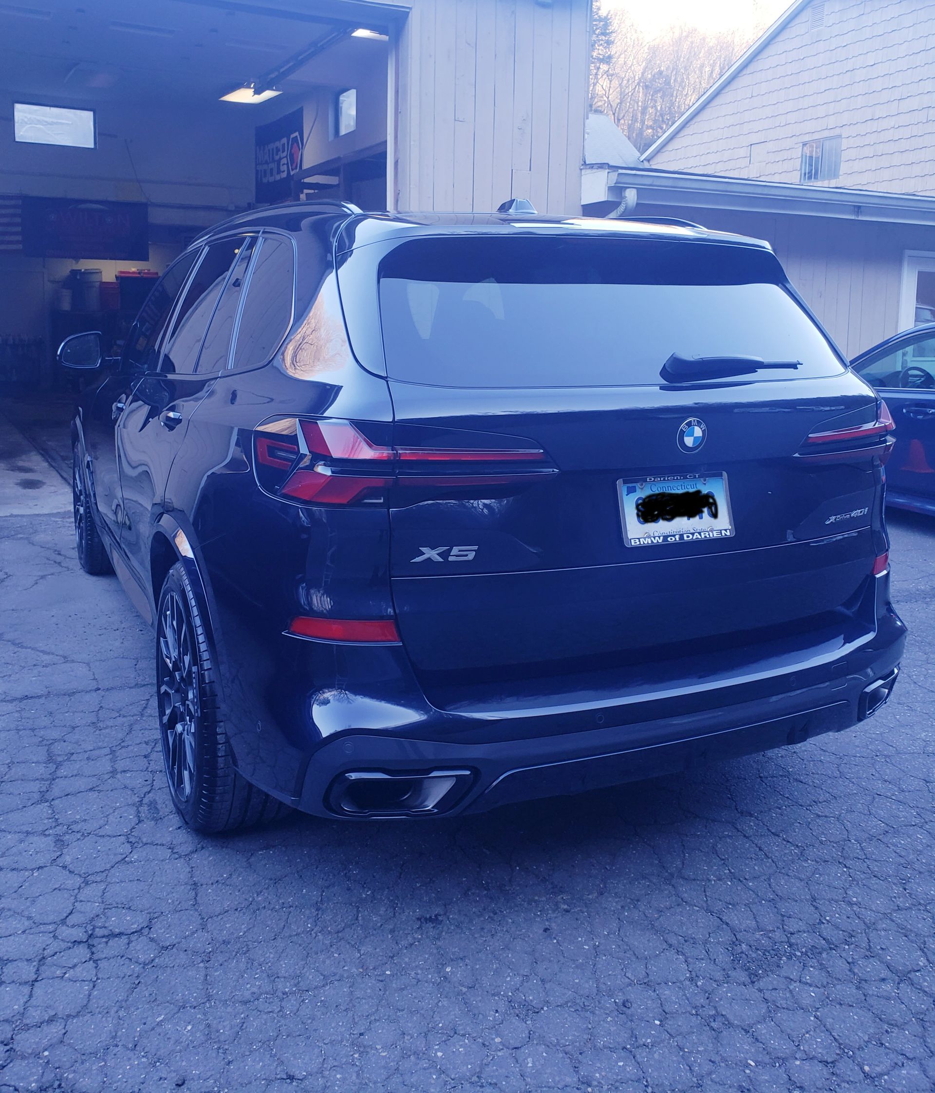 A black bmw is parked in front of a garage