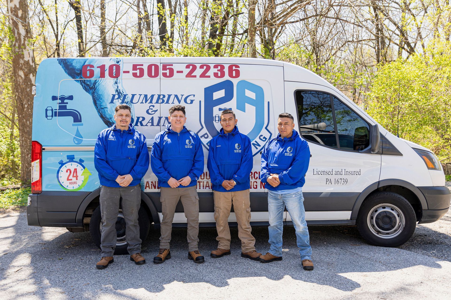 Four people in blue shirts standing in front of a service van with PA Service Group branding and phone number.