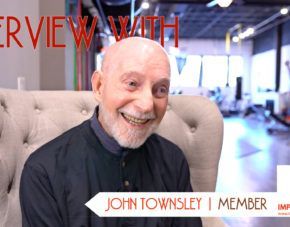 Smiling man in a gray chair with “John Townsley | Member” caption in an interview setting