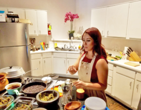 Person cooking in a bright kitchen with several pots and bowls on the counter