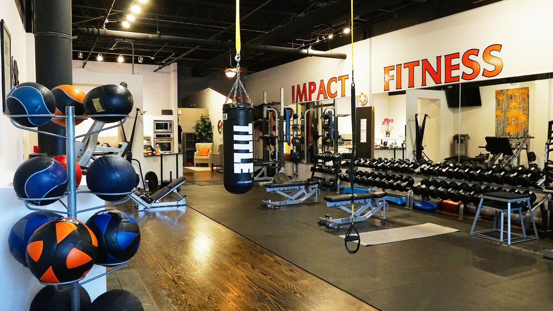 Gym interior with punching bag, dumbbells, medicine balls, and workout benches under bold FITNESS signage