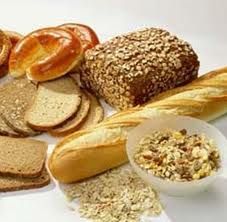 Assorted breads and rolls with a bowl of cereal or granola on a white background