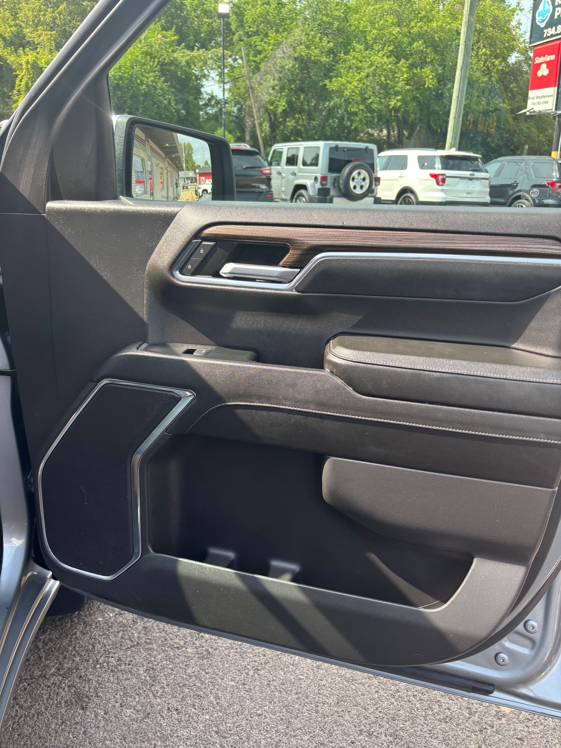 Close-up of a car door interior with black trim, silver handle, and wood accent panel
