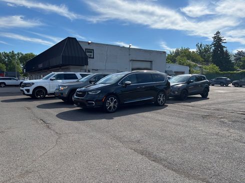 Parking lot with several parked cars beside a low white building under a clear sky