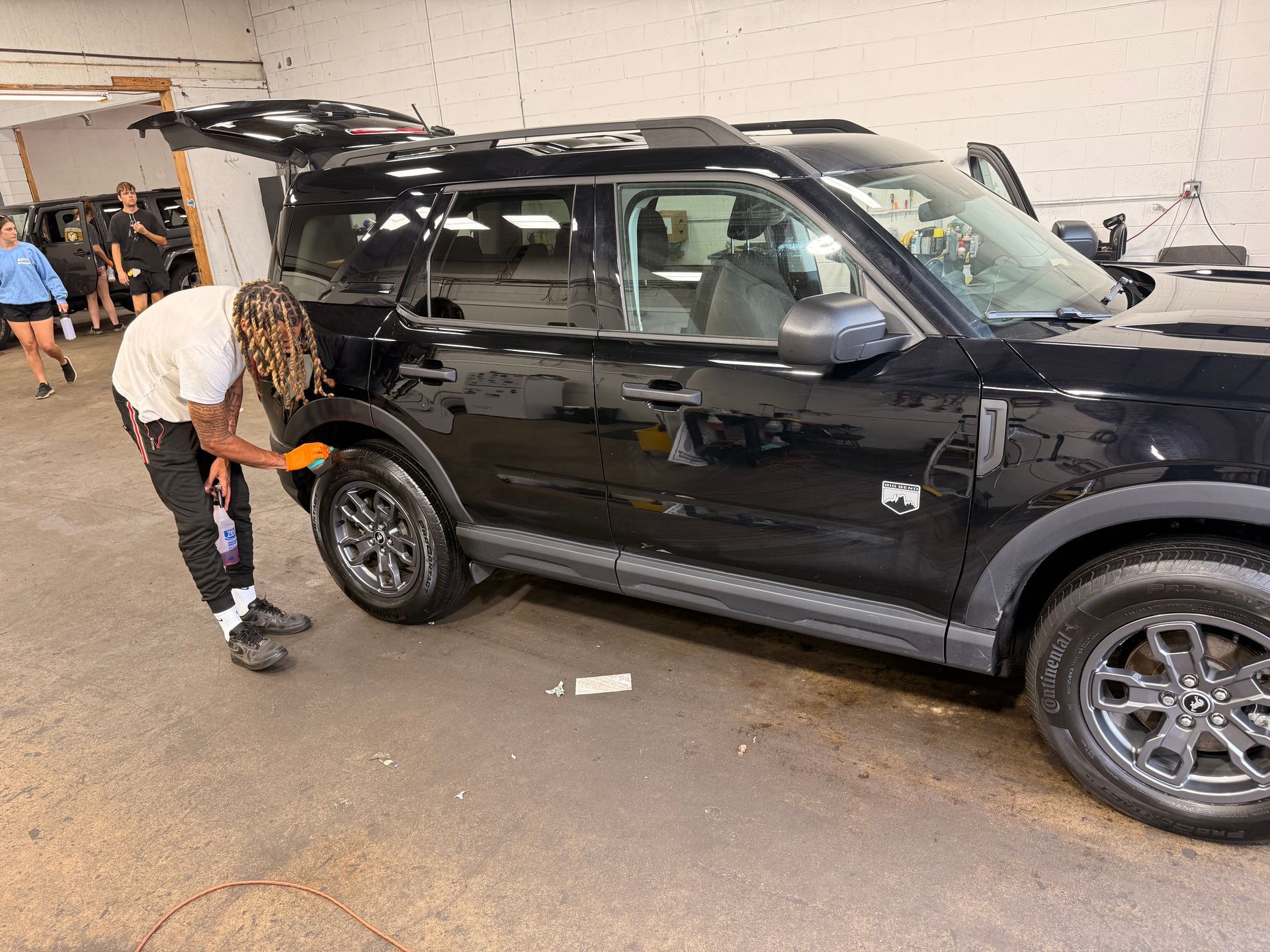 Person changing a tire on a black SUV in a parking garage