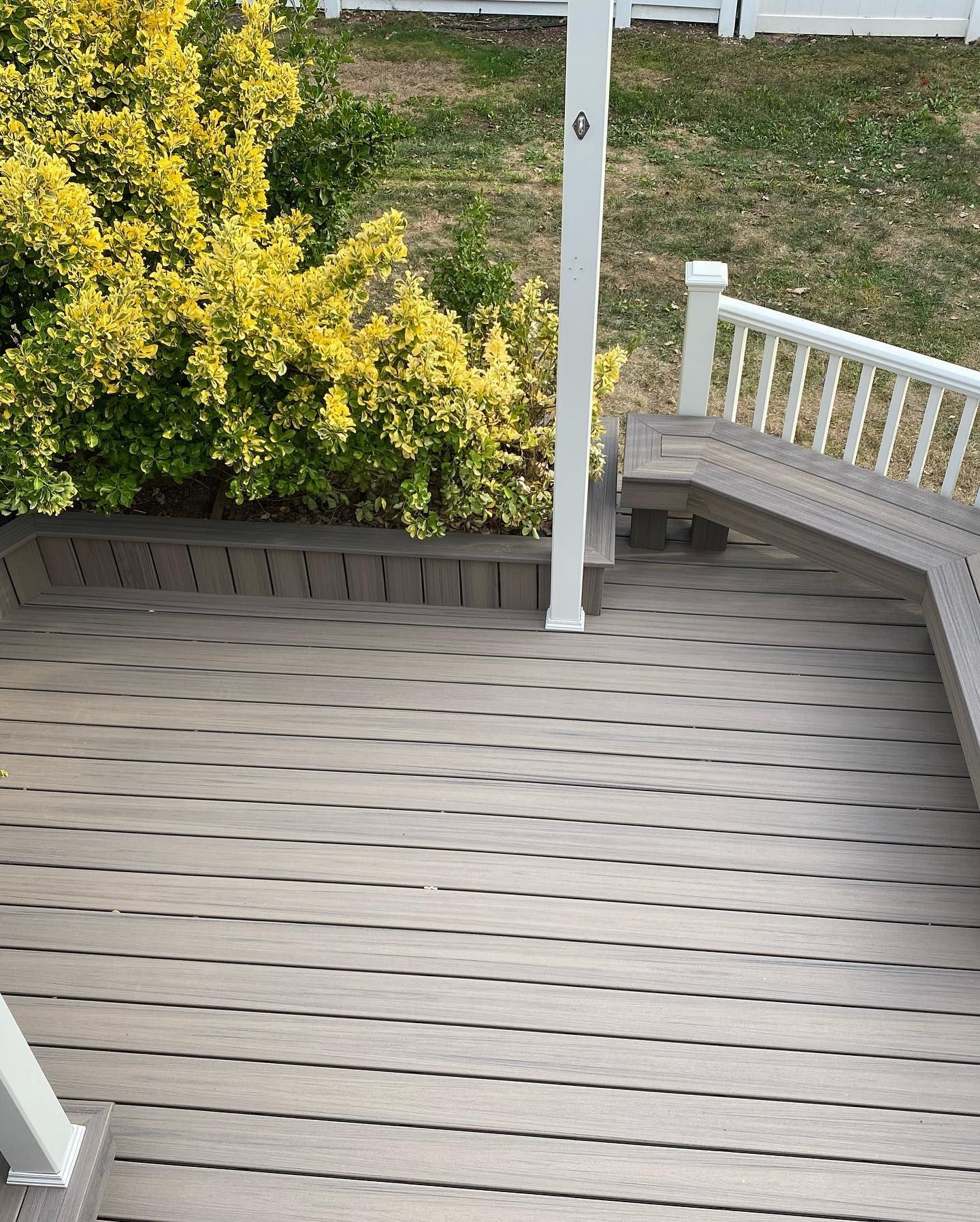 A large wooden deck with stairs and benches in front of a house.