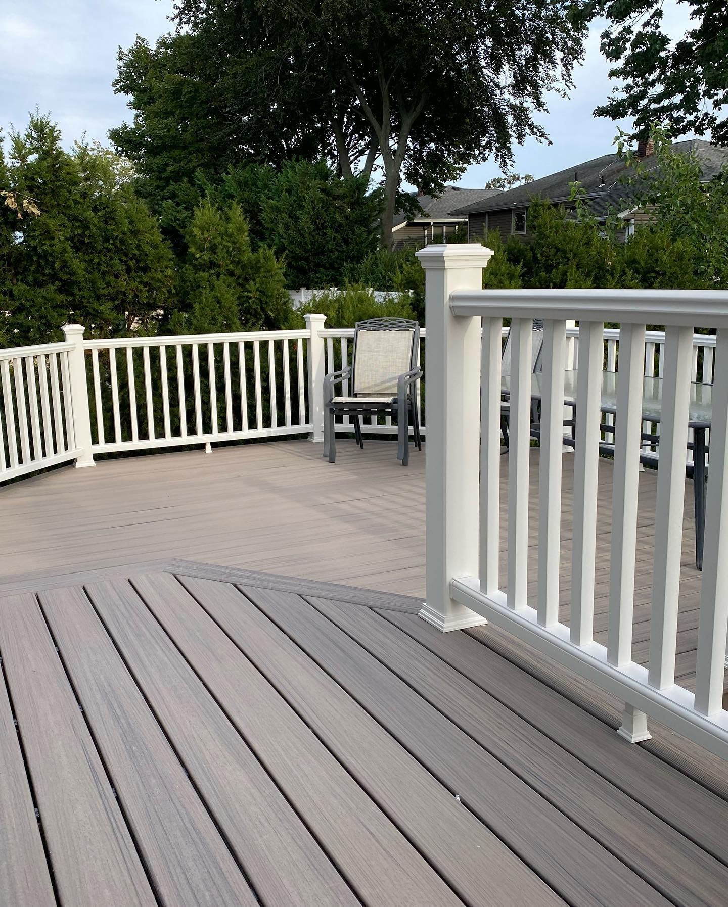 A deck with a white railing and chairs on it.