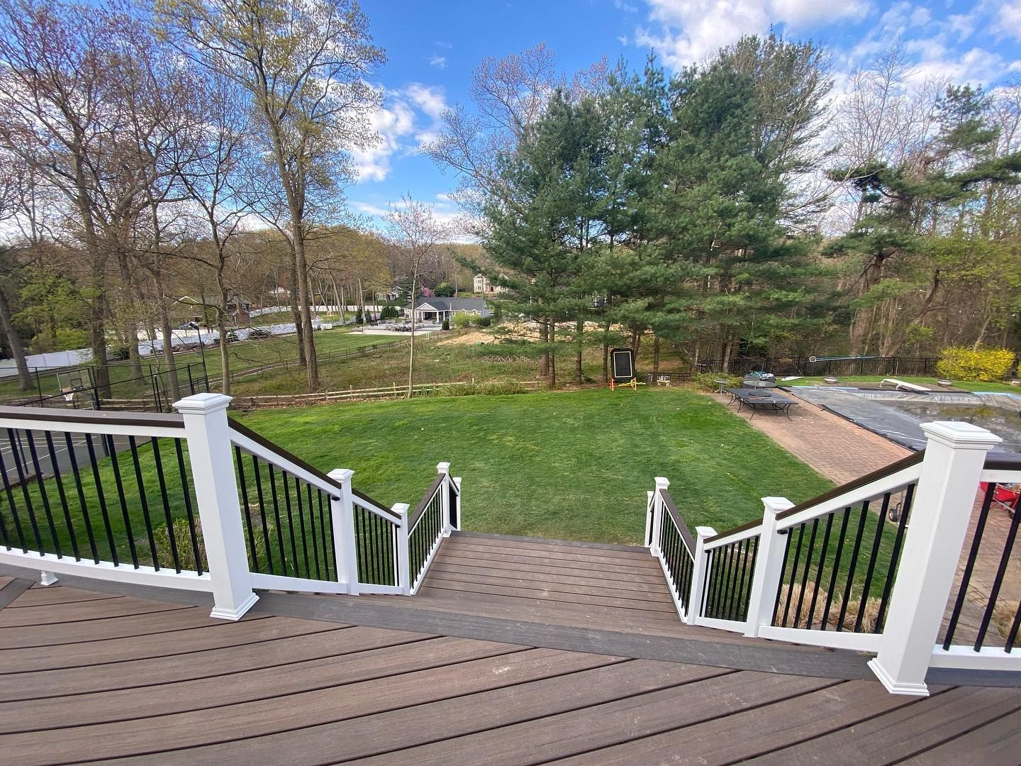 A deck with stairs leading up to a lush green yard.
