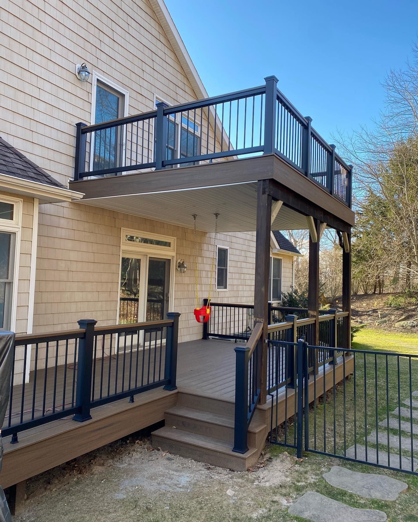 A large deck with a black railing is on the back of a house.