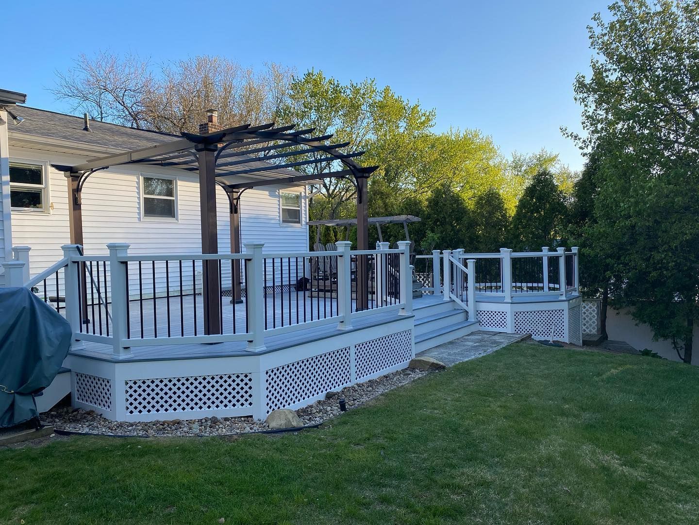 A white house with a large deck and a pergola in the backyard.