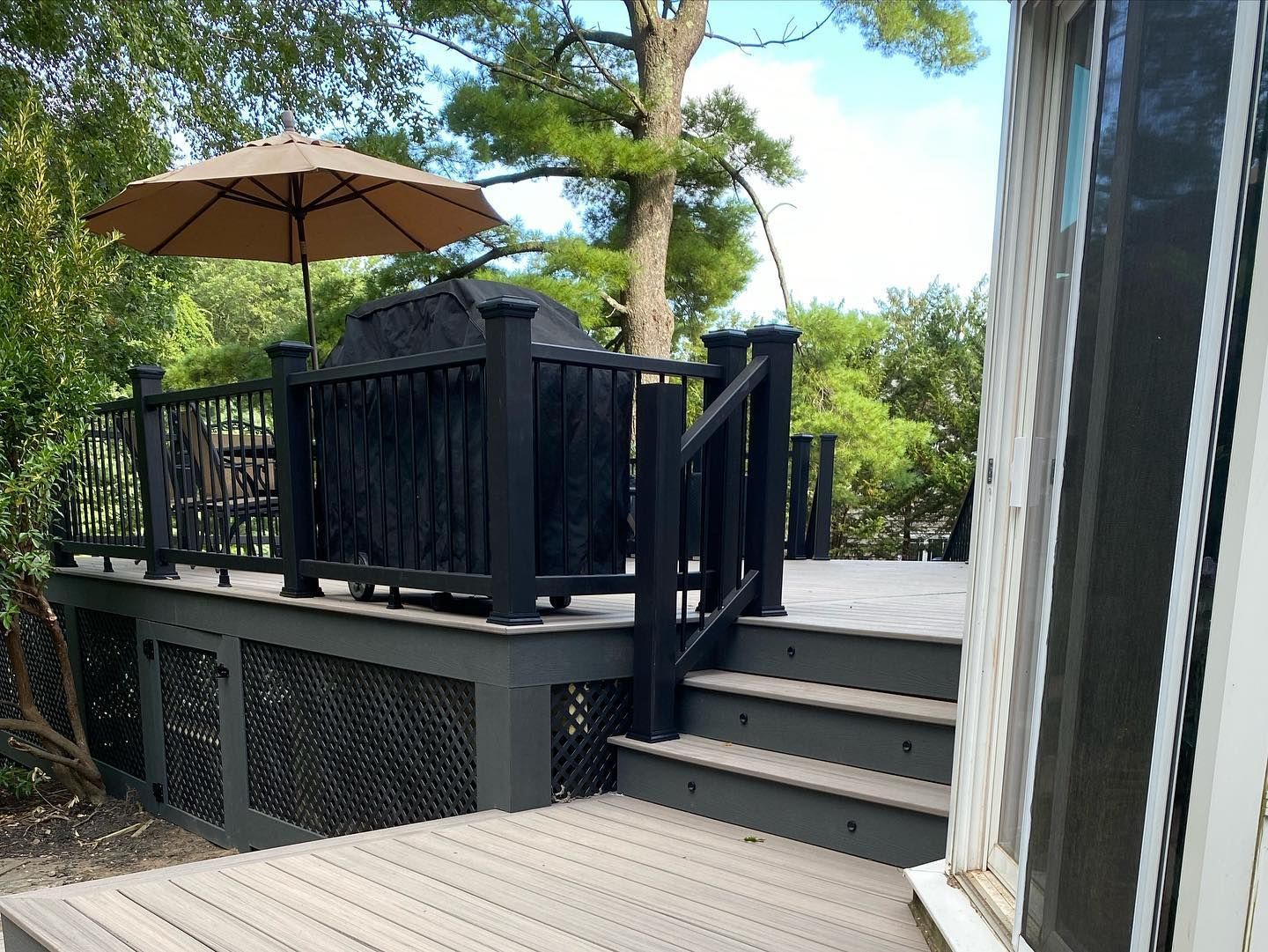 A deck with a grill and umbrella on it.